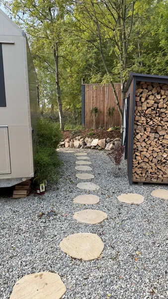 Stone path behind the cabin leading to woodshed with birch firewood