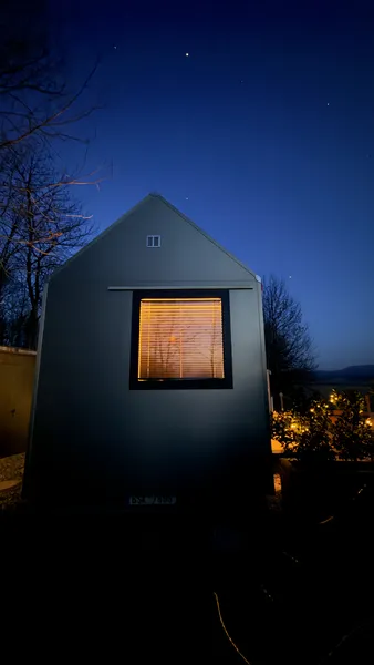 Cabin under starry sky — gable silhouette with lit window
