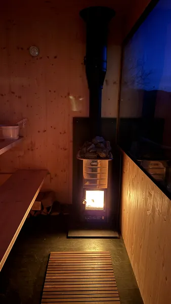 Wood-fired sauna interior with Harvia stove and burning fire