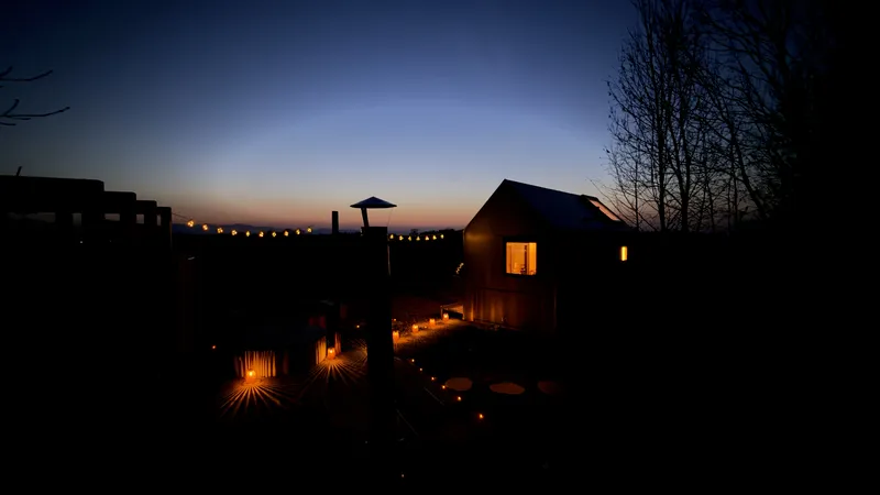 Dusk at Johanka glamping — sauna and cabin silhouettes against blue sky