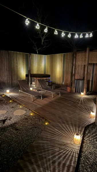 Wellness area at night — loungers under string lights and hot tub